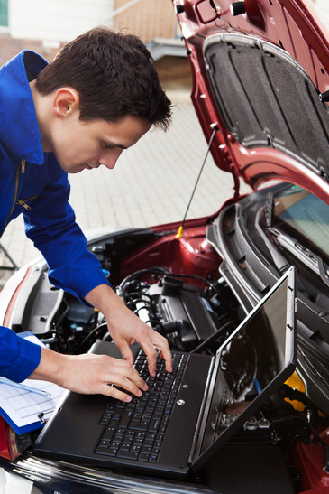 Mechanic Using Laptop While Repairing Car