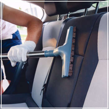 man vacuuming the interior of a car