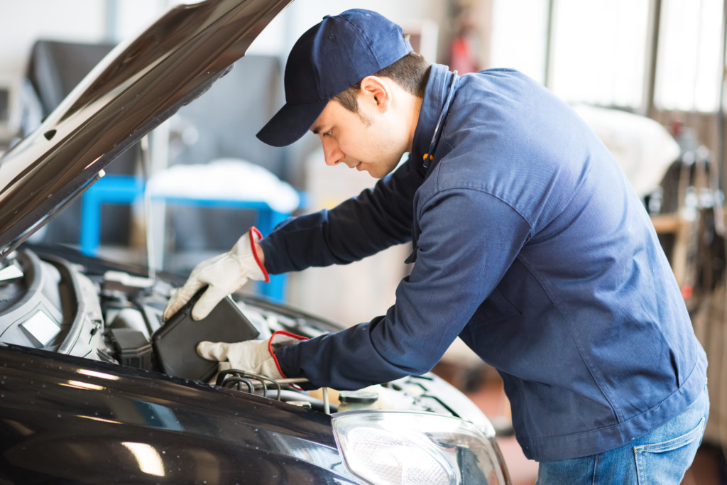 mechanic putting oil in a car engine