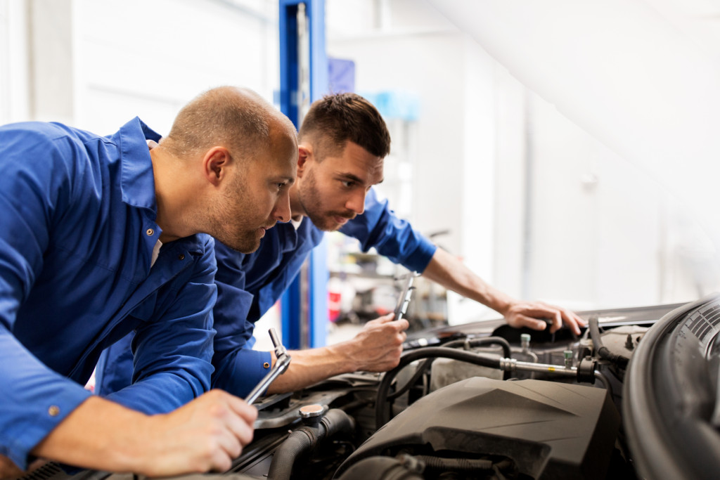 Two mechanics inspecting a vehicle engine 