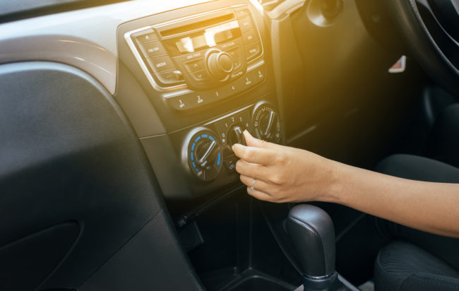 Woman turning on car air conditioning system