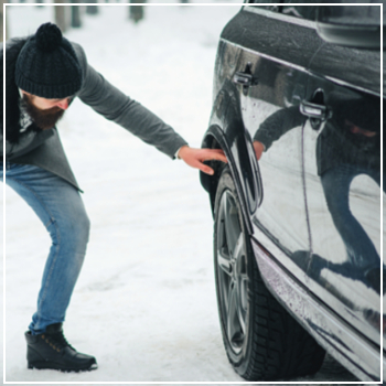 man checking tire in snow