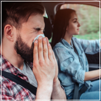 man sneezing in car