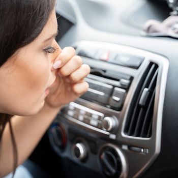 woman covering nose in car