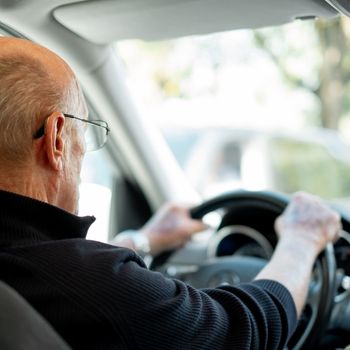 man with hands on steering wheel