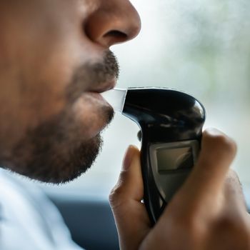man taking breathalyzer test inside car